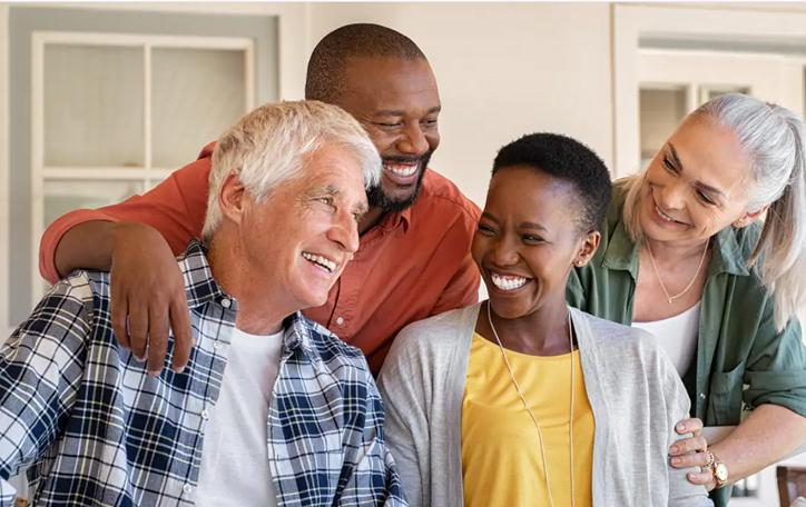 Portrait of senior man in wheelchair using laptop at retirement home with nurse assisting him