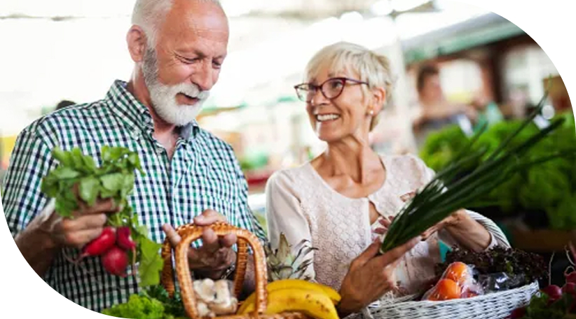 Portrait of senior man in wheelchair using laptop at retirement home with nurse assisting him